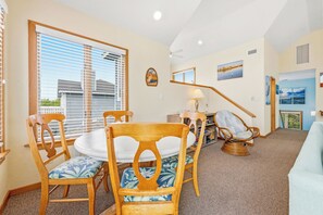 A dining area with a round table and chairs, a lamp, and a view of the outside.