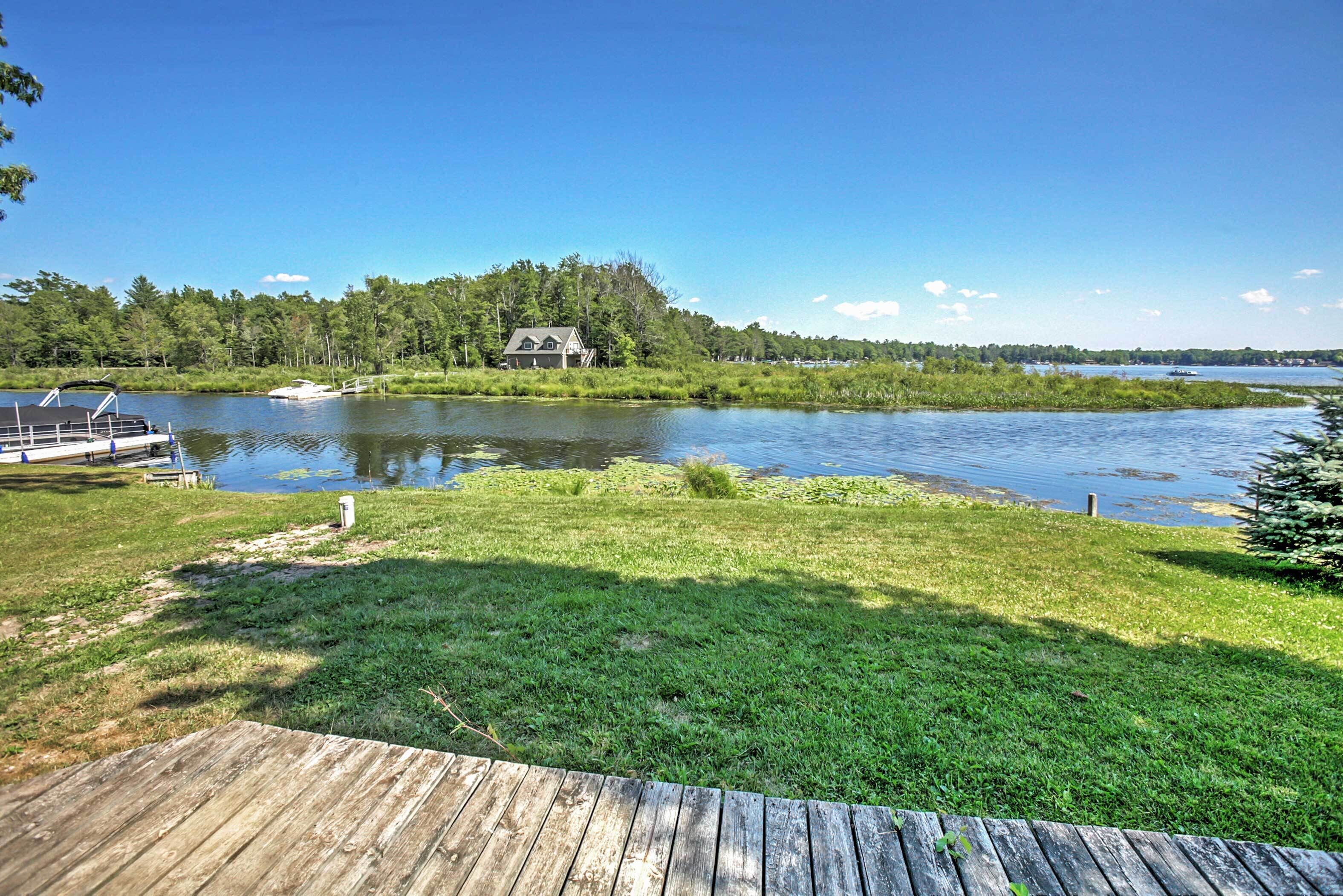 Una proprietà sul lago con un molo, una zona verde e una casa sullo sfondo.