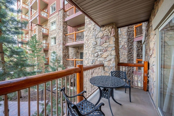 A balcony with stone walls, wooden railings, and a table with chairs.