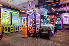 An indoor arcade with various gaming machines, including a claw machine and a foosball table.