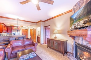 A living room with a fireplace, a sofa, a coffee table, and a television mounted on the wall.