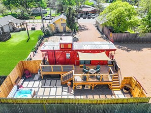 Un edificio rojo con el nombre "ROCK ISLAND" en la fachada, una terraza con sillas, un jacuzzi y una piscina.