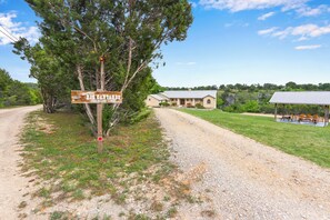 A gravel road leading to a building with a sign that reads 'Welcome to Rio Cantando The Bees Family.'