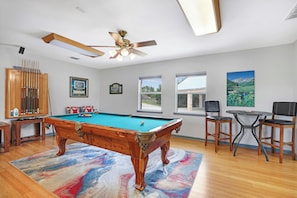A pool table with a ceiling fan, a billiards rack, and a pool cue case. - Rio Cantando I Blanco River, Pool, Hot Tub, Game Room (Wimberley)