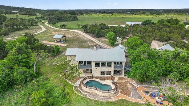 A large house with a swimming pool, surrounded by a landscaped garden and a view of the countryside. - Rio Cantando I Blanco River, Pool, Hot Tub, Game Room (Wimberley)