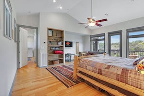 A bedroom with a bed, a ceiling fan, a large window, and a view of the outdoors. - Rio Cantando I Blanco River, Pool, Hot Tub, Game Room (Wimberley)