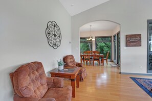 A spacious living room with a wooden dining table and chairs, a large decorative wall piece, and a sign indicating the property name and establishment year. - Rio Cantando I Blanco River, Pool, Hot Tub, Game Room (Wimberley)