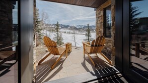 A wooden deck with two Adirondack chairs facing a snowy mountain landscape. - Stunning Mountain Home by InvitedHome | Hot Tub, Game Room, Golf Course, Hiking (Mountain Village)
