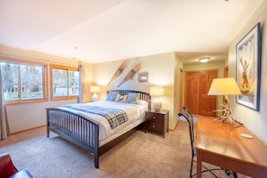 A bedroom with a bed, bedside tables, a desk, and a chair. There are windows and a door visible. - All Seasons 104 at Park City Mountain (Park City)