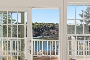 Vista a través de una puerta que da a una terraza de madera y un río al fondo.