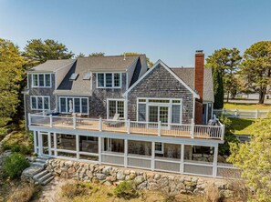 A two-story house with a balcony, stone steps, and a white picket fence.