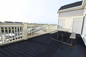 A balcony with a white railing, a small table, and a door. - Large, spacious 3 bedroom condo with free WiFi, a boat slip, and an outdoor pool located uptown on the bay water with breathtaking view of bay! (Ocean City)