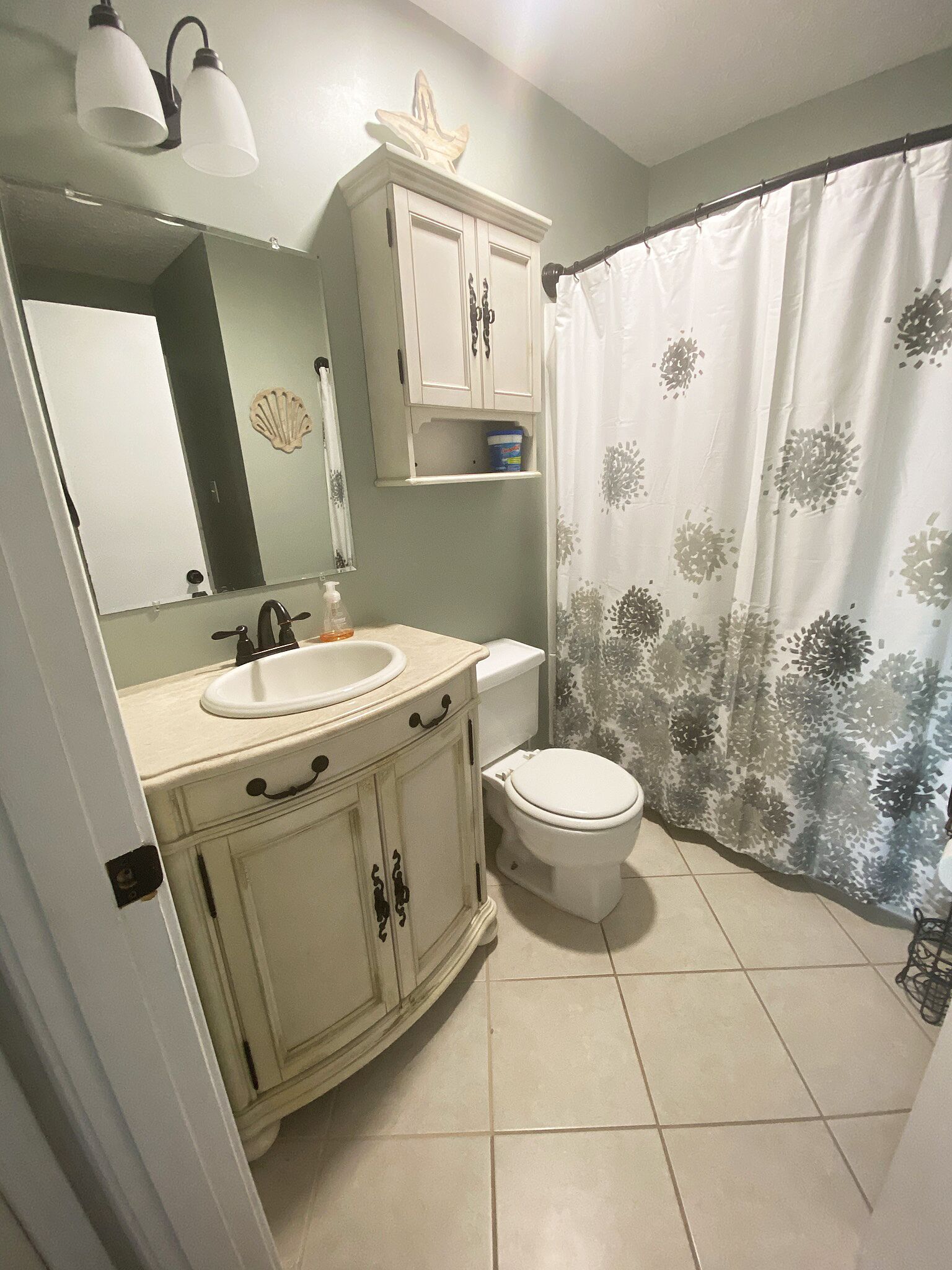 Een badkamer met een wastafel, spiegel, kast, toilet en douchegordijn.