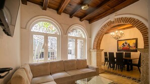 Una sala de estar con un sofá color crema, una mesa de centro de vidrio y un comedor con una mesa y sillas.