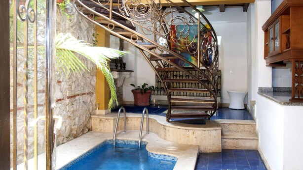 Una piscina con una escalera en espiral, un muro de piedra y un suelo de baldosas.