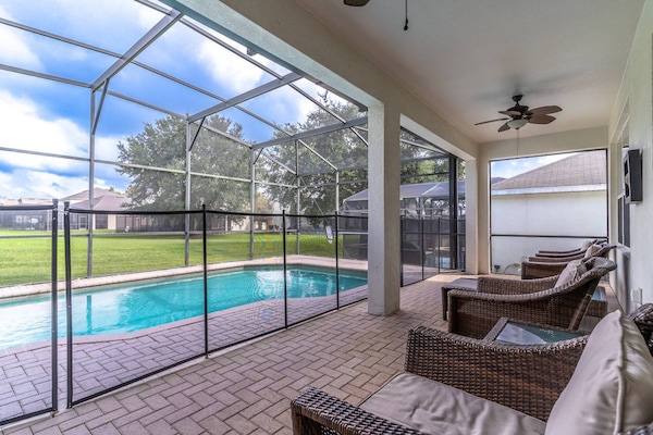 Lounge seating on the rear patio with a fenced in, fully enclosed pool.
