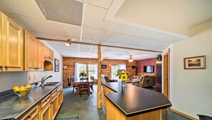Una cocina con armarios de madera, encimera negra y un comedor con mesa y sillas.
