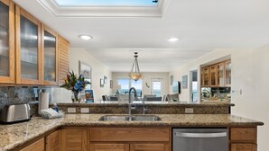 A modern kitchen with granite countertops, wooden cabinets, a stainless steel sink, and a dishwasher.