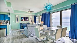 Uma sala de estar moderna com uma mesa de jantar, cadeiras e vista para o mar.