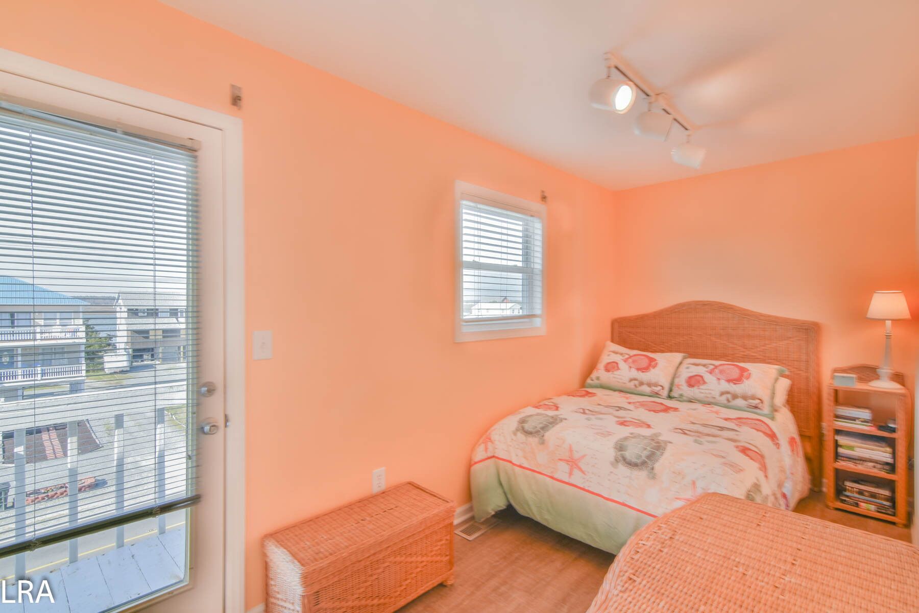 A bedroom with a bed, a nightstand, a lamp, a window, and a view of buildings outside.