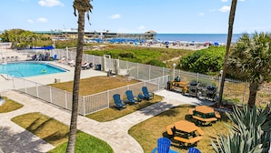Área da piscina com espreguiçadeiras, churrasqueira e vista para a praia.