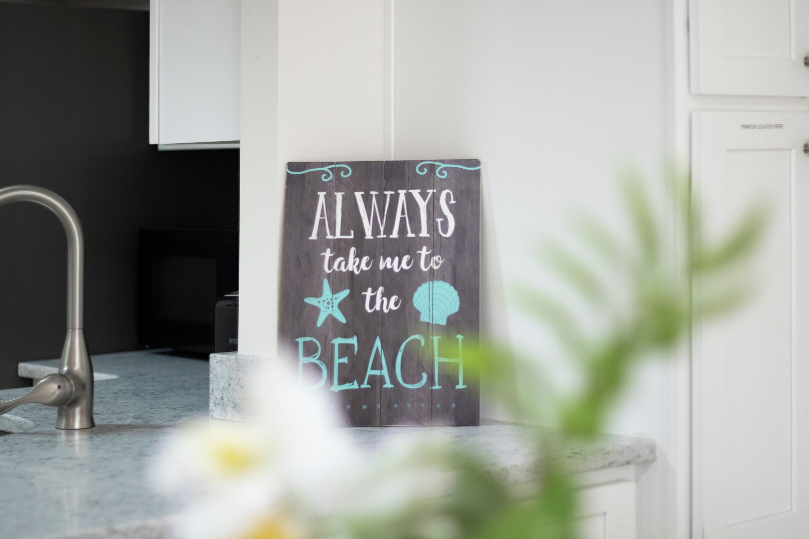 A kitchen with a sign that reads "ALWAYS take me to the BEACH."