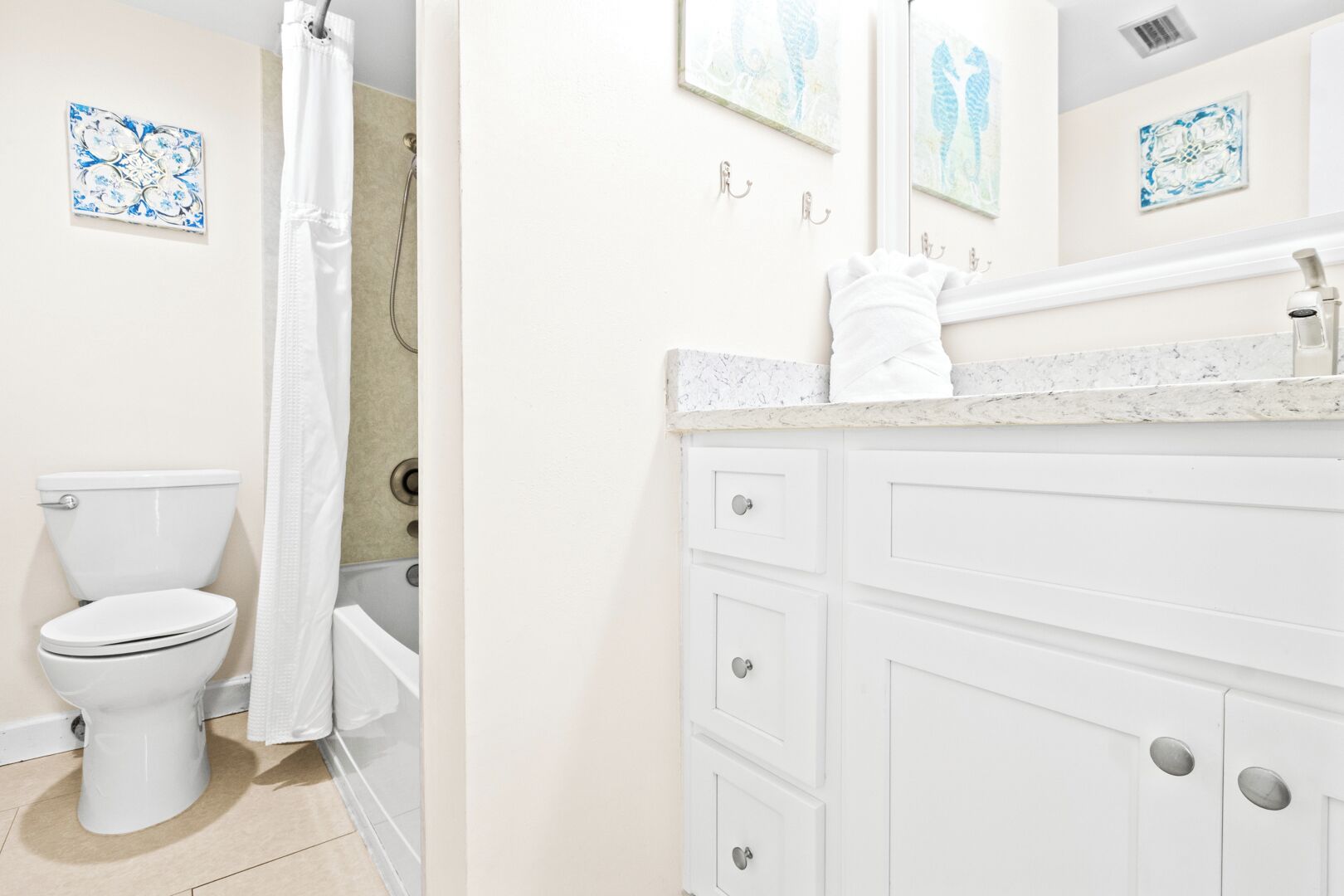 A bathroom with a toilet, shower, and a vanity with a mirror.