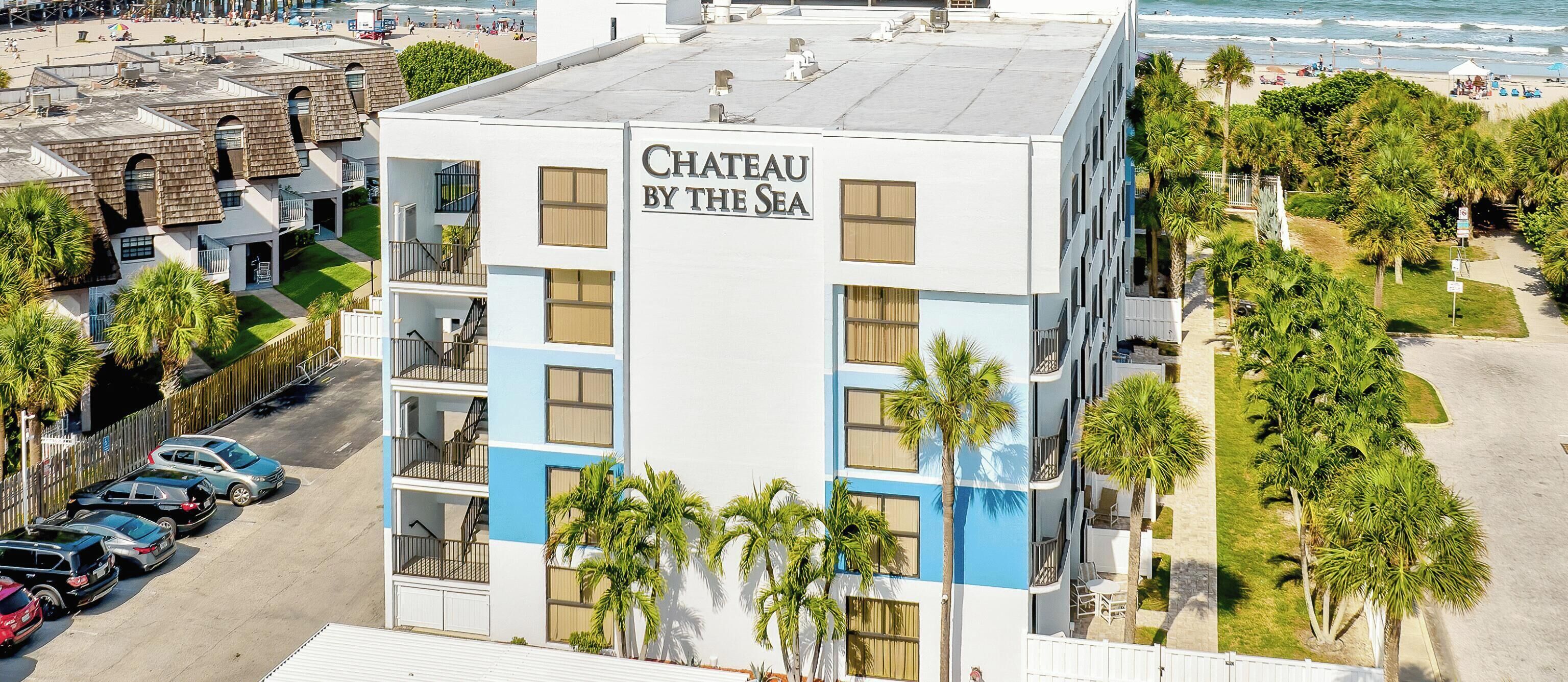 A hotel named 'Chateau By The Sea' with a beach view, located on a beachfront property.