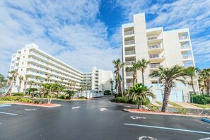 A multi-story hotel with a central courtyard, palm trees, and a clear sky.