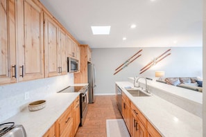 A modern kitchen with wooden cabinets, a stainless steel refrigerator, and a built-in oven.