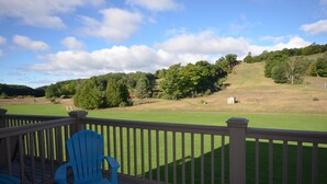 A deck with a view of a grassy field and trees. - Leelanau County, 4-brm 4-bath. A/C, Pool, 5 mins to Lk Michigan Beach (Cedar)