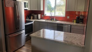 A modern kitchen with stainless steel appliances, a marble countertop, and a window with a view of the outdoors. - Leelanau County, 4-brm 4-bath. A/C, Pool, 5 mins to Lk Michigan Beach (Cedar)