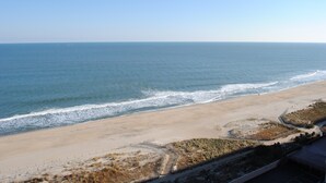 A beach with a sandy shore and a clear view of the ocean. - Comfortable 2 bedroom oceanfront condo popping with color that has free WiFi, and a balcony with an amazing ocean view located uptown just steps to the beach! (Ocean City)