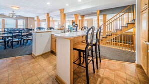 Une cuisine spacieuse avec un grand îlot central, des chaises en bois et un escalier menant à un autre niveau.
