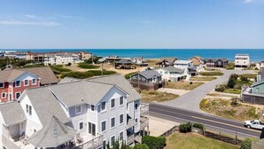 Une zone résidentielle côtière avec des maisons, une route et l’océan en arrière-plan.