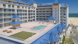 Ein mehrstöckiges Hotel mit Poolbereich, mehreren Balkonen und Blick auf den Strand.