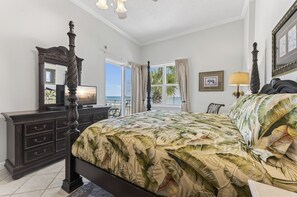 Quarto com cama grande, penteadeira, espelho e vista para o mar.