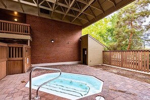 Un espace piscine extérieur abrité, doté d’un mur en briques, d’une terrasse en bois et d’un jardin clôturé.