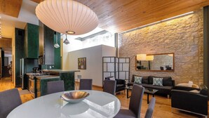 A modern interior with a round dining table, a kitchen area with a stove, and a stone wall. - Luxury Stay | Views, Game Room & Chef’s Kitchen (Austin)