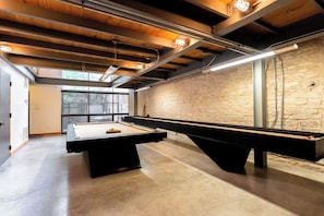 A pool table in a room with exposed wooden beams and a stone wall.