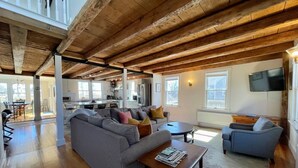 A spacious living area with a wooden ceiling, a grey sofa, a blue armchair, and a coffee table.