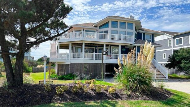 A two-story house with a balcony, surrounded by a well-maintained lawn and a tree. - WH888- Beautiful! With 4 BRs (2 Masters), Private Pool, Hot Tub & Wet Bar! (Corolla)
