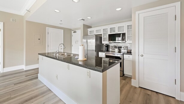 A modern kitchen with a central island, white cabinetry, and stainless steel appliances. - Elegant 2BR | Pool, Lake Views | Remodeled June 24 (Henderson)