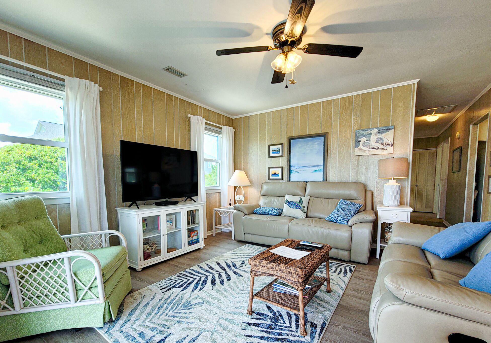 A living room with a television, two sofas, a coffee table, and a ceiling fan.