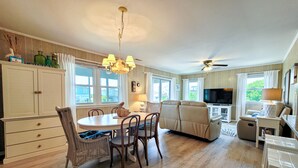 A spacious living area with a dining table, chairs, a sofa, and a television. - Merri Mac – Breezy Stays by the Sea (Surf City)