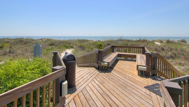 Eine Holzterrasse mit Blick auf Strand und Meer.