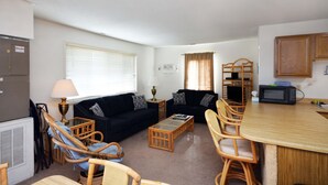 A compact living space with a sofa, chairs, a coffee table, a dining table, a microwave, and a refrigerator. - Spacious, quaint 2 bedroom condo with free WiFi and a large balcony located downtown on the bayside just two blocks from the beach! (Ocean City)