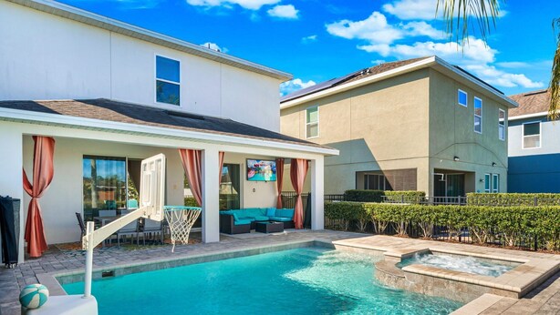 A swimming pool with a hot tub, outdoor seating, and a covered patio area. - Stylish Retreat with Great Themed Rooms at Encore (Kissimmee)