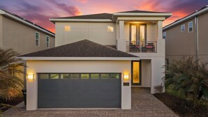 A modern two-story house with a garage, a balcony, and a driveway. - Stylish Retreat with Great Themed Rooms at Encore (Kissimmee)
