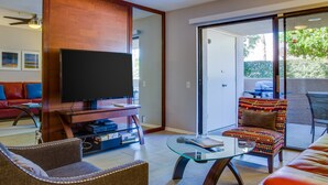 A modern living room with a flat-screen TV, a glass coffee table, and a sofa.